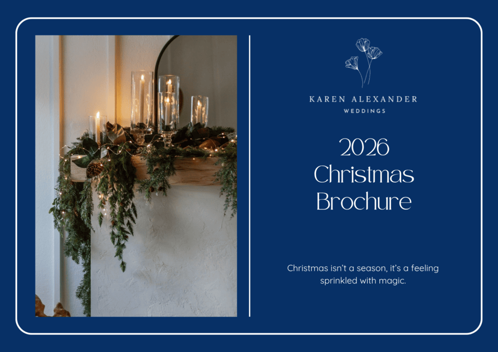 A decorated fireplace mantelpiece with candles and greenery next to a blue panel reading “2026 Christmas Brochure” for Karen Alexander Weddings.
